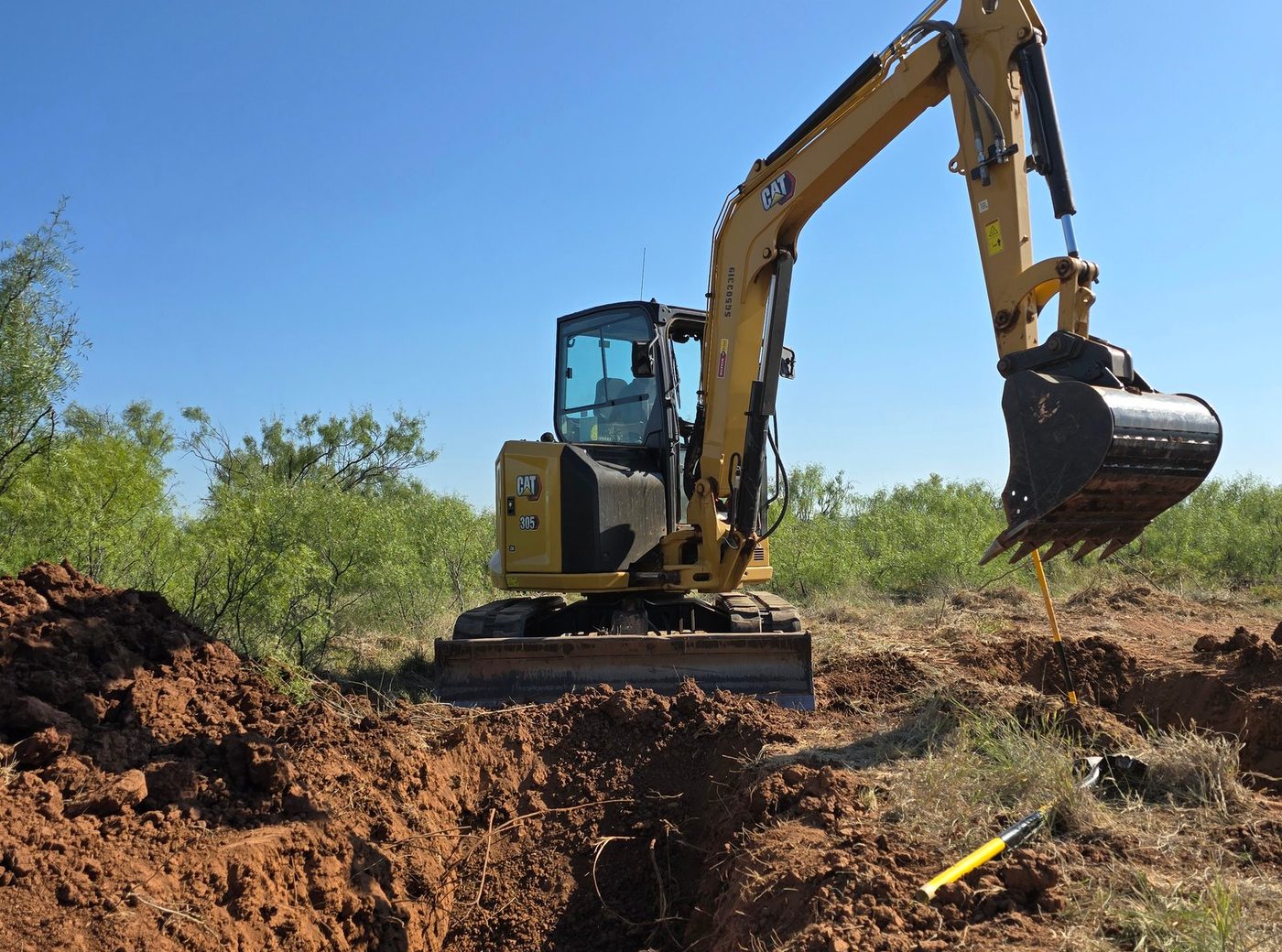 Tracked excavator working red dirt on a West Texas site