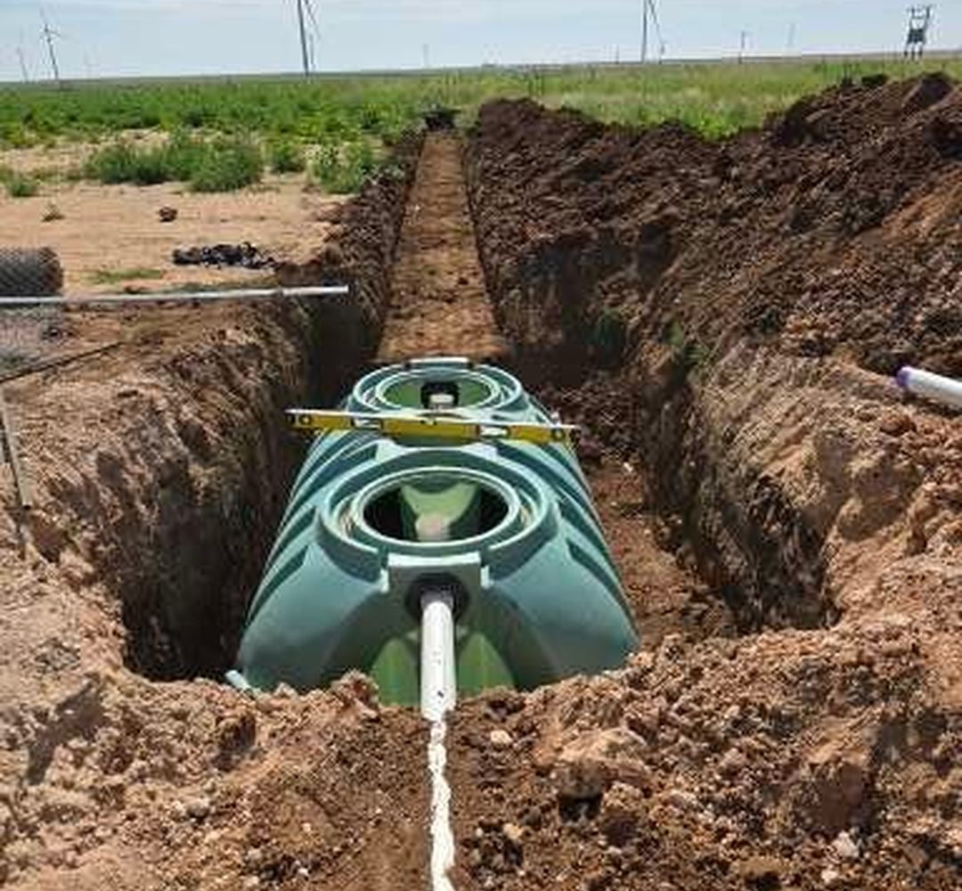 Septic tank set in a red-dirt trench in West Texas